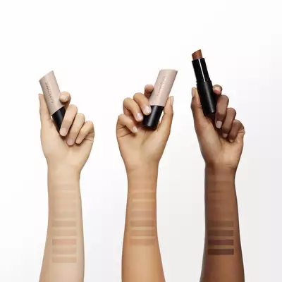 Tiered arrangement of three Lancome Teint Idole Shape Stick Foundation, Highlighter and Blush in white, beige, and pink.